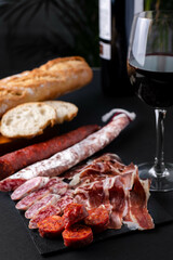Spanish snack with chorizo, salchichon, jamon, fresh baguette and a glass of red wine.