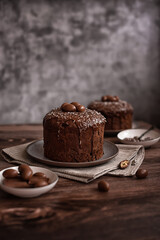Fototapeta na wymiar Easter cake: traditional Russian Easter yeast pastry Kulich - chocolate cake with raisins and chocolate icing on a dark wooden table
