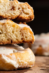 Cut of a cinnamon roll with cream cheese on a stone background close up. Front view stack of baked yeast buns.