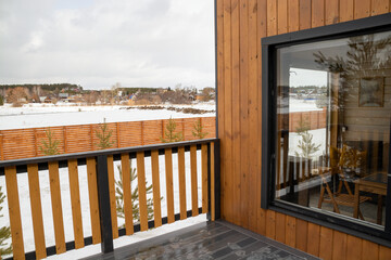 scandinavian house with panoramic window and terrace in the winter forest.