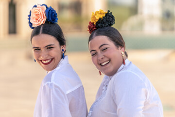 portrait of two teenage girls in flamenco dresses laughing loudly