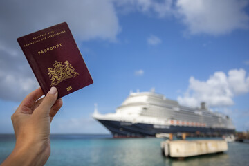 Female hand holding Dutch passport on the background of the sea.