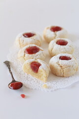 Traditional Sicilian almond biscuits, decorated with cherry jam and powdered sugar on the white background, traditional Italian food, minimalist style, close-up