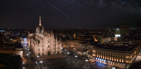 Fototapeta na wymiar Aerial view of Piazza Duomo in front of the gothic cathedral in the center. Aerial view of the night Milan sky with stars and milky way galaxy in Italy.