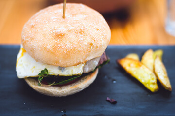 Hamburger with baked potatoes on a dark plate.