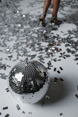 Disco ball near attractive woman legs. Silver.