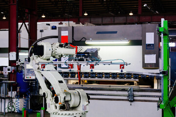 Robotic arm working with metal sheet at hydraulic bending machine