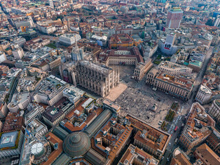 Aerial view of Piazza Duomo in front of the gothic cathedral in the center. Drone view of the gallery and rooftops during the day. Milan. Italy,