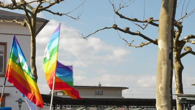 Rainbow flags blowing in the wind at a peace demonstration. The word pace is painted on the flags. Anti war. Slow motion.
