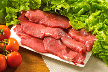 Raw rib eye beef steak with tomatoes and green salads