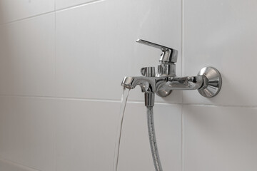 Close up of chrome faucet and shower in on a background of white bags in the bathroom. Bathroom...