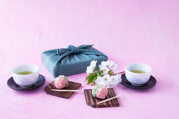 Obraz na płótnie Canvas 春の和菓子　さくらと若葉の練り切りと緑茶と桜の小枝（オオシマザクラ）と風呂敷包み