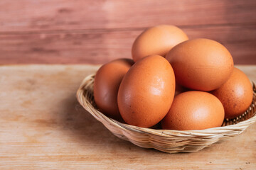 basket of fresh chicken eggs on a wooden table from agriculture farm.