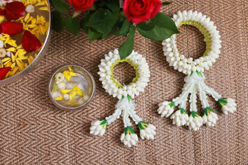 Obraz na płótnie Canvas Beautiful Traditional Jasmine garland with colorful flower petals toping on water in bowl on brown mat, Songkran festival background
