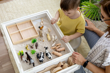 Montessori material. Little boy with his mom explores the farm animals in the game. Flat lay