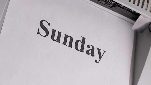 Sheets of office paper come out of the printer with the names of the days of the week from Sunday to Saturday, close-up, the concept of the rapid passage of time