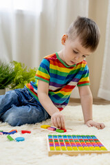 Montessori material. Boy study at a home school. Son in rainbow clothes
