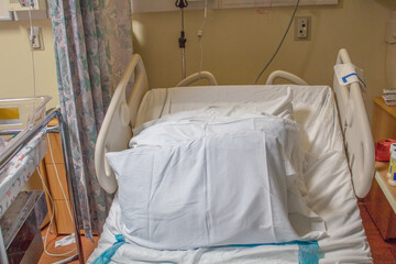 Empty hospital bed with pillows in maternity ward.
