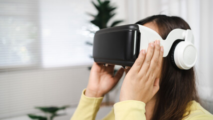 Young Asian woman gamer wearing virtual reality touching air during the VR experience  Future home technology player hobby playful enjoyment concept.