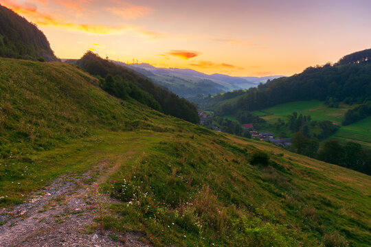 rural valley of carpathian mountains at dawn. wonderful summer scenery with grass and herbs on the fields and meadows, forested slopes and hills in morning light