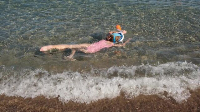 Little girl with swimming mask, snorkeling in shallow waters of beautiful sea