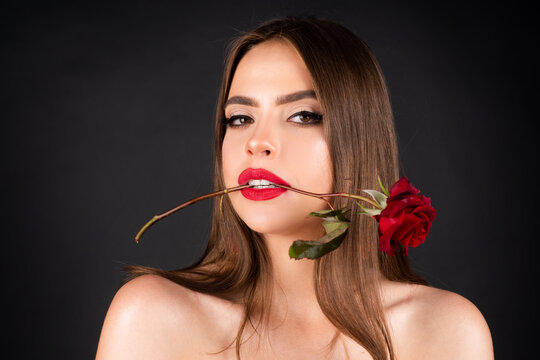 Seductive sensual woman holding red rose with teeth. Close-up portrait of young beautiful sexy woman with red rose. Birthday day.