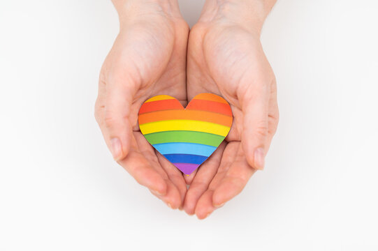 Female hands with rainbow paper heart isolated on white background. 
