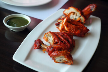 Tandoori chicken, a traditional Indian dish, is served on a white plate.