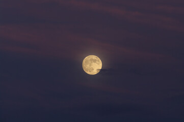 Beautiful full moon rising over the Mojave desert shown against a cloudy sky.