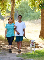 A stroll through the park. Shot of a young couple with their dog enjoying a day in nature.