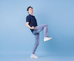 Full length image of young Asian man posing on blue background