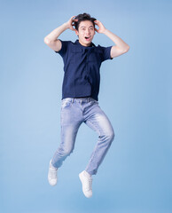 Full length image of young Asian man posing on blue background