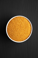 Brown Demerara Sugar in a Bowl on a black background, top view. Flat lay, overhead, from above.