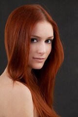 Her beauty is a light in the darkness. Portrait of a gorgeous young redheaded woman against a black background.