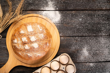 freshly baked wheat bread on a wooden kitchen table, top view.