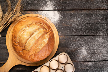 freshly baked wheat bread on a wooden kitchen table, top view.