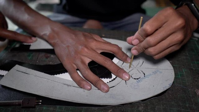 Shoe craftsmen are making brogue wingtip shoes made of leather which are done manually in a small home workshop
