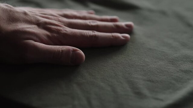 Slow motion handheld shot of man hand touching green cotton fabric
