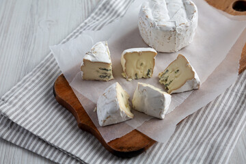 Alpine Blue Cheese on a rustic wooden board, side view.