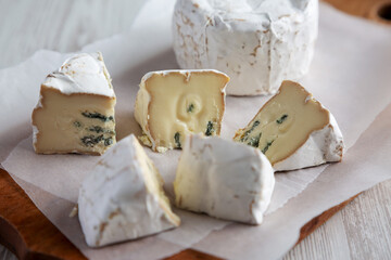 Alpine Blue Cheese on a rustic wooden board, side view. Close-up.