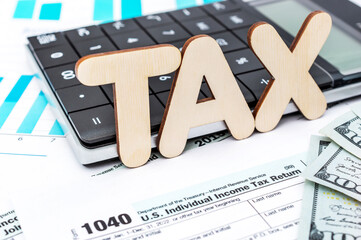 Word "TAX" with calculator on the tax form and financial documents.