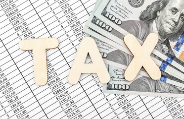 Word "Tax" with dollar bills on documents with financial data. Business concept.