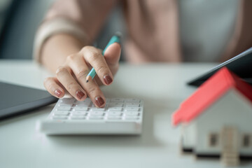 Close-up of business woman hand using calculator to calculate business data, accountancy document at home office.