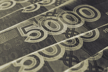 Russian banknotes 5000 rubles close-up. Fragment of a note with a focus on the denomination figure. Dark gray and yellow money background or wallpaper. Banking economy and currency in Russia. Macro
