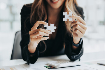 Businesswoman holding a two piece puzzle to shape, running a startup company, strategizing to make...