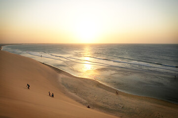 People step up sand dunes at sunset
