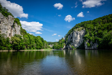 Fototapeta premium Rocks of the Danube Gorge with green forest, blue sky, water and beach of the Danube. Danube Gorge in Bavaria Germany.