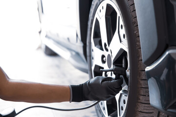 Auto mechanic checking air pressure and inflating car tires. Concept of car care service and maintenance or fix the car leaky or flat tire.