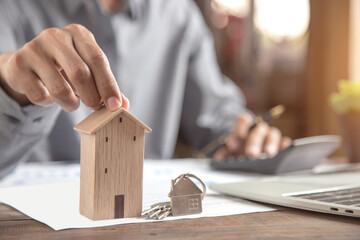 Fototapeta na wymiar Close up wooden house with house key on desk with documents for bank loan for housing or purchase of a home, plan for installment payments.