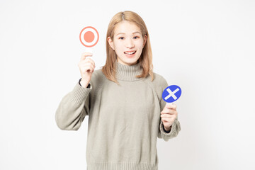 白い背景の前に立ってOKとNGのプラカードを見せている若い女性